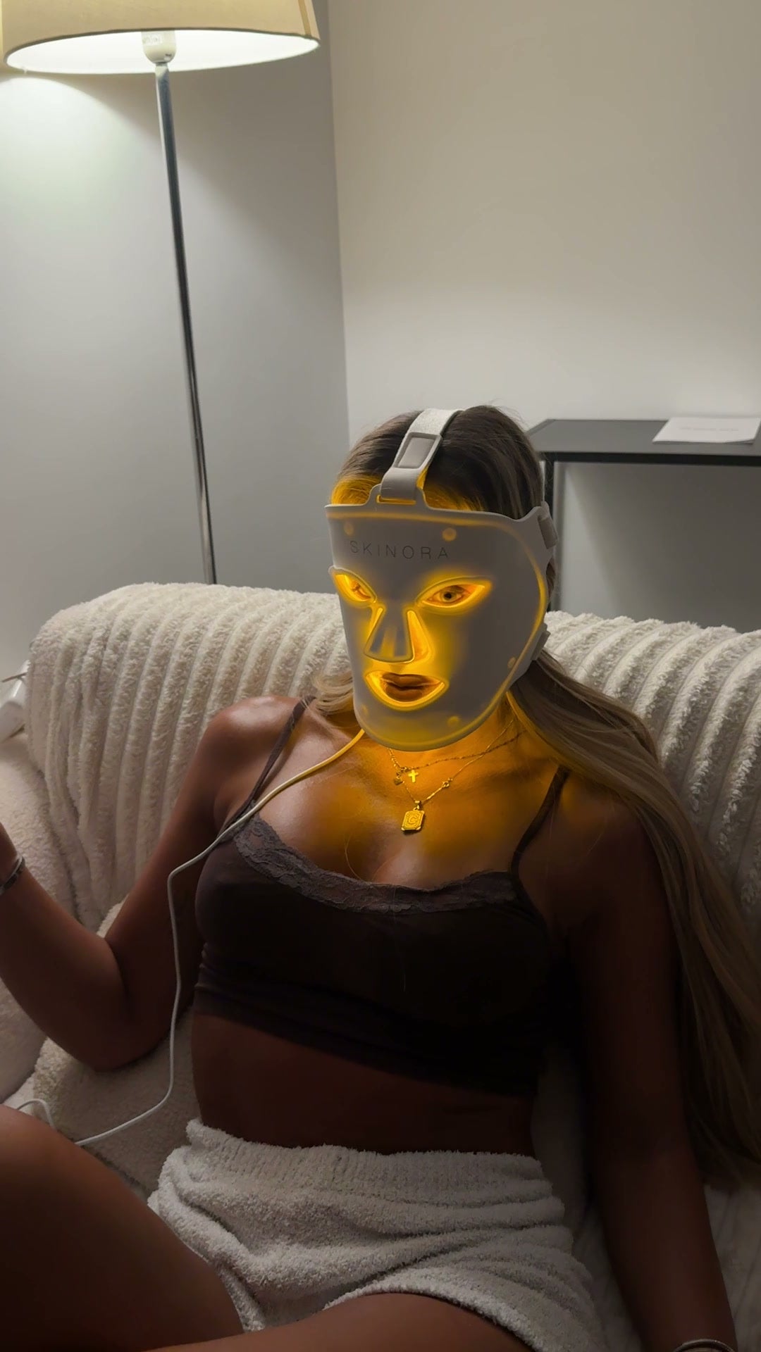 Masque LED visage Skinora allumé en lumière jaune, porté lors d'une séance du soir